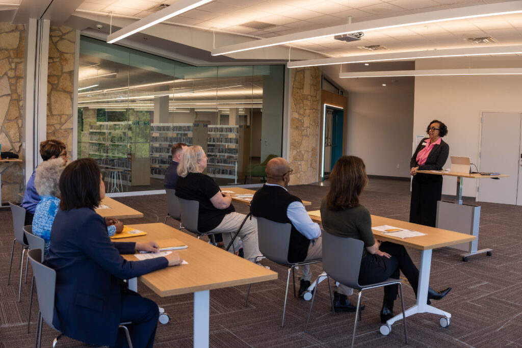 Instructor leads adult literacy class in a modern library setting.