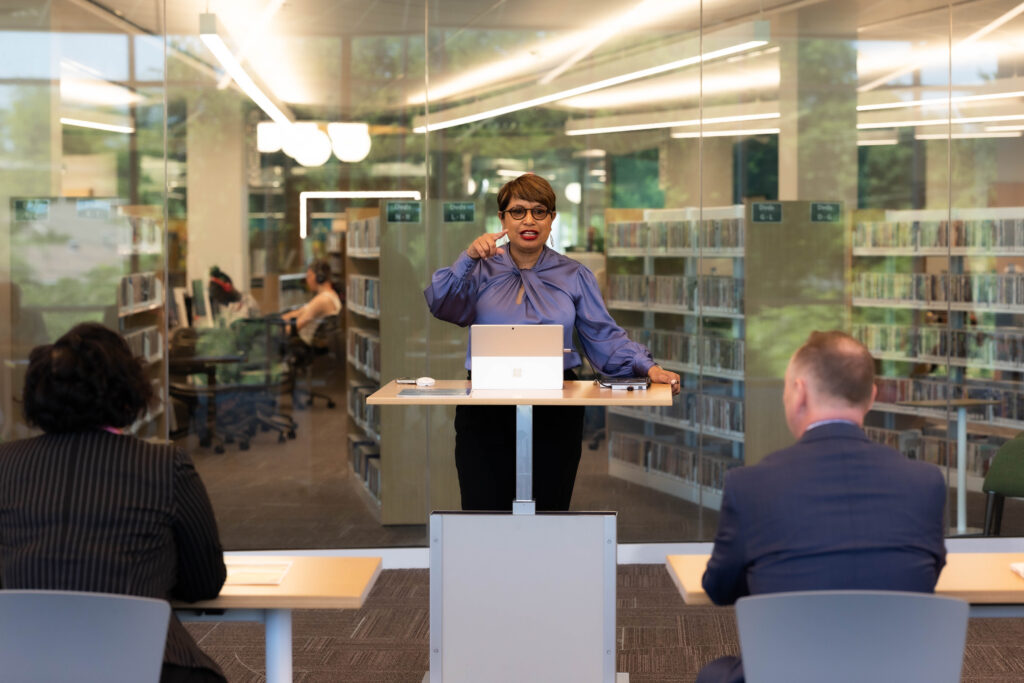 Confident speaker leads adult literacy session inside a modern library learning space.