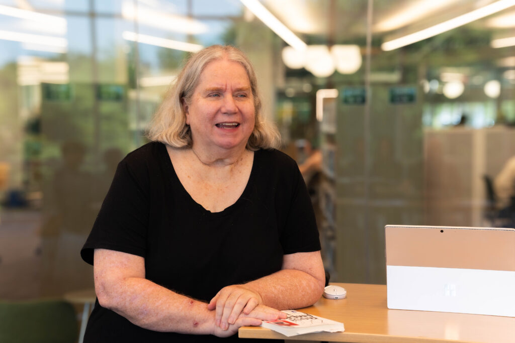 Smiling woman participates in a discussion at an Oklahoma City adult learning center with a book and laptop in front of her.