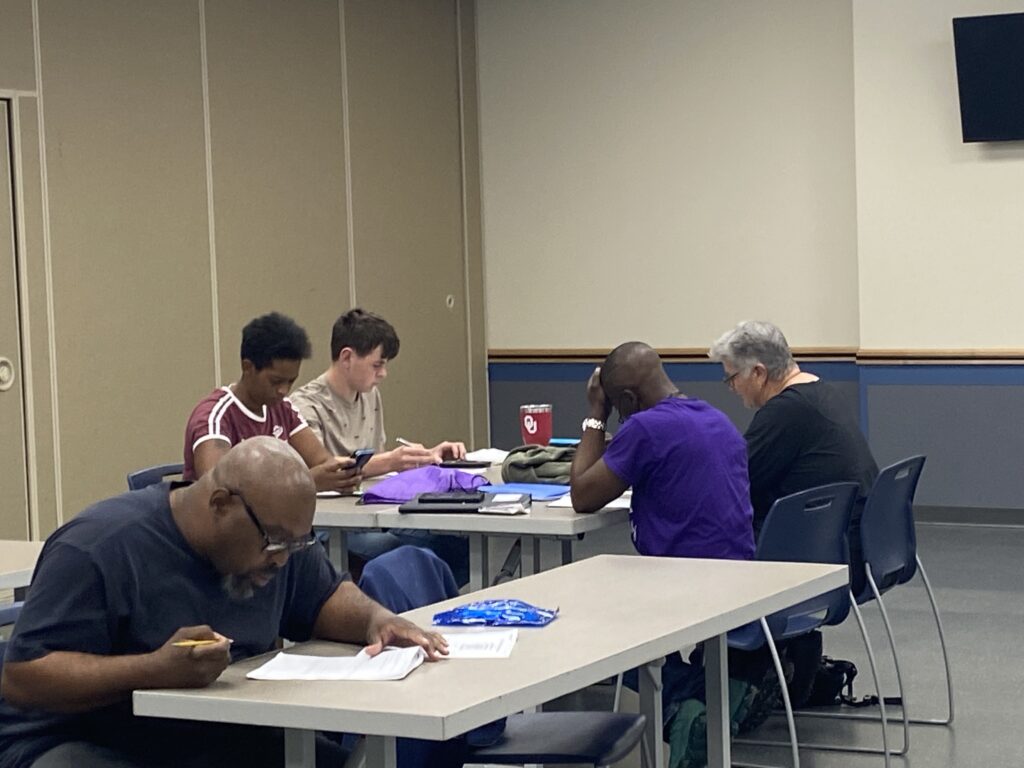 Group of adult learners and volunteers working together in a classroom setting, highlighting volunteer opportunities in education.
