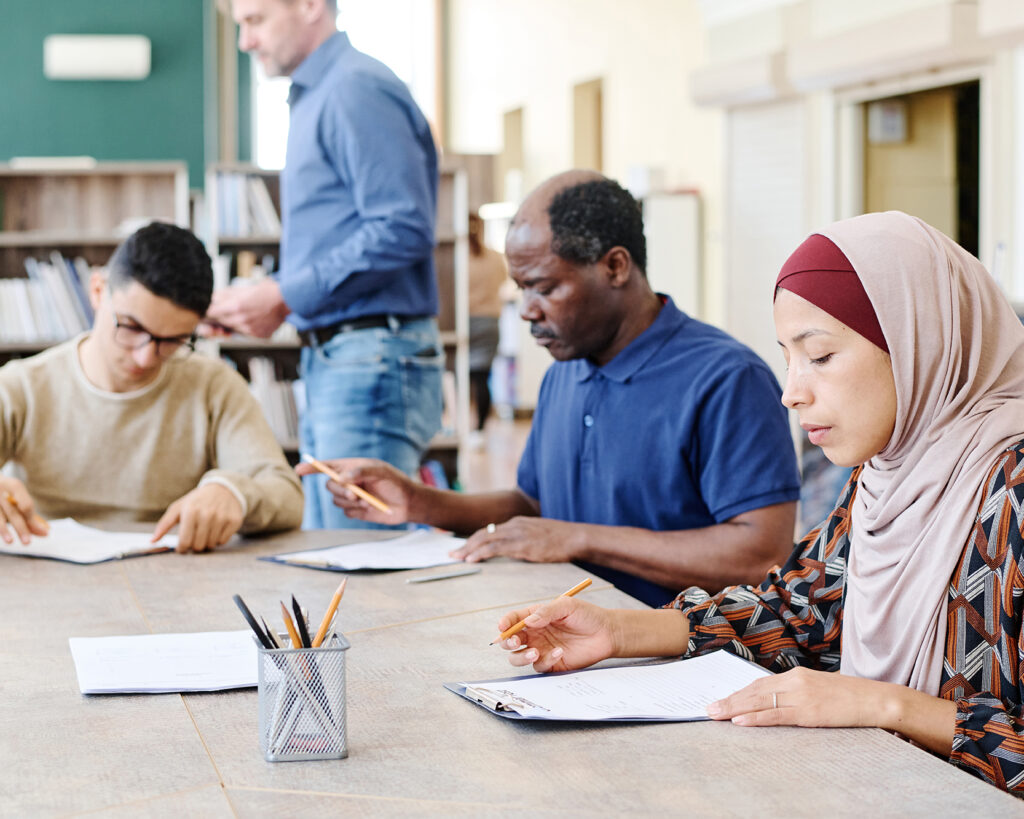 Diverse group of adult students working on written assignments during adult learning classes.