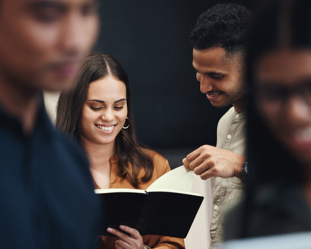 Two adult students smiling and reading together during adult learning classes.